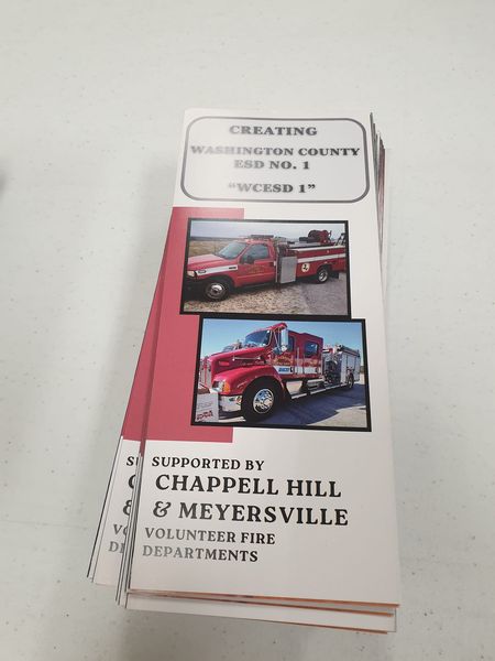 A stack of brochures titled "Creating Washington County ESD No. 1” with photos of fire trucks. The bottom text reads "Supported by Chappell Hill & Meyersville Volunteer Fire Departments.